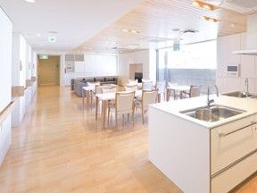 白い家具でそろえたリビングダイニング。キッチンも白く大きい。壁には手すりが付いている。