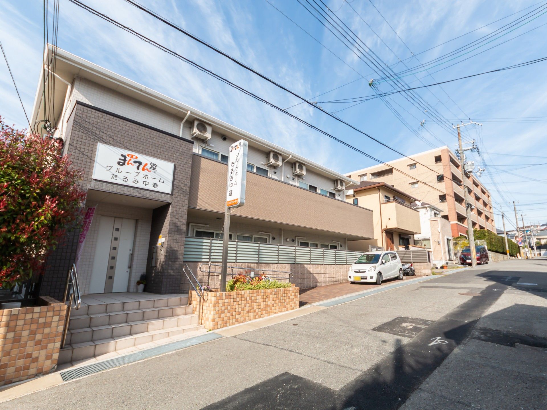 ブラウン系の2階建ての建物。玄関部分には屋根があり、2階部分にはベランダが付いている。