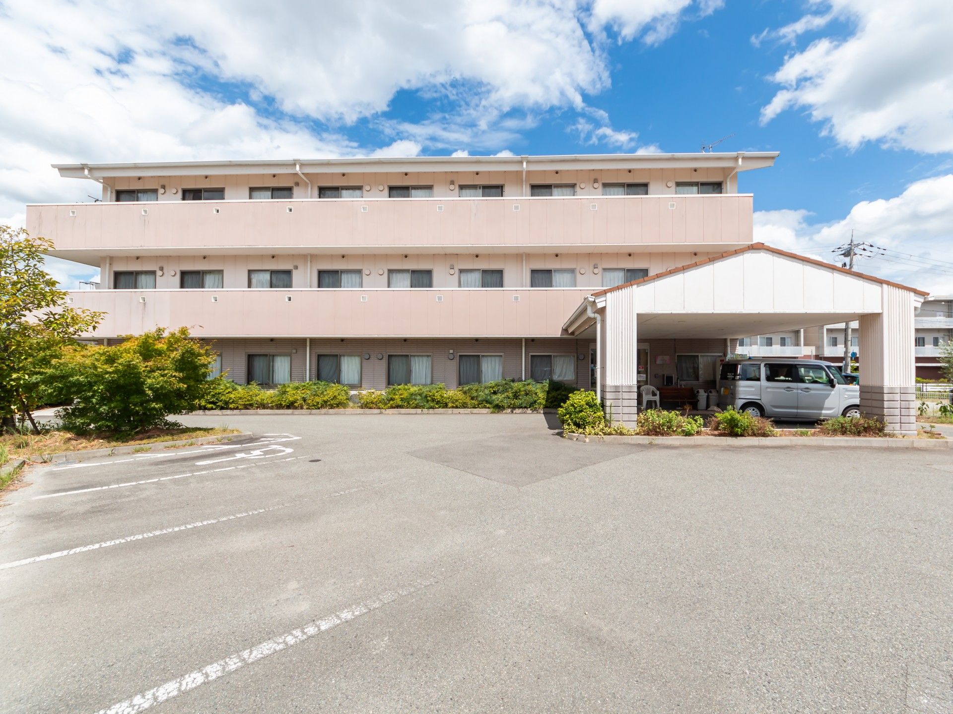 水の入ったコップを持った女性スタッフが薬を飲もうとしている高齢女性のそばにいる。