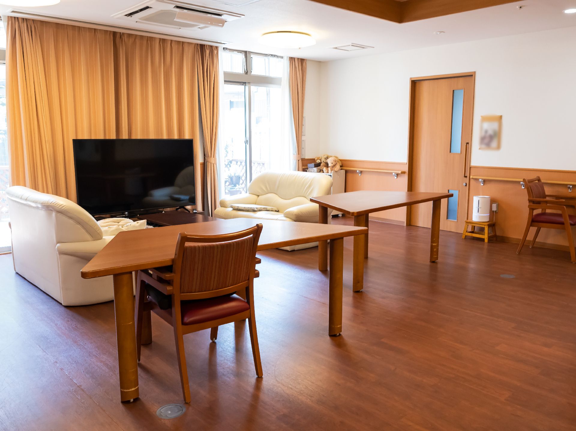 テレビが設置され、大きなテーブル、ソファーが置かれているリビング