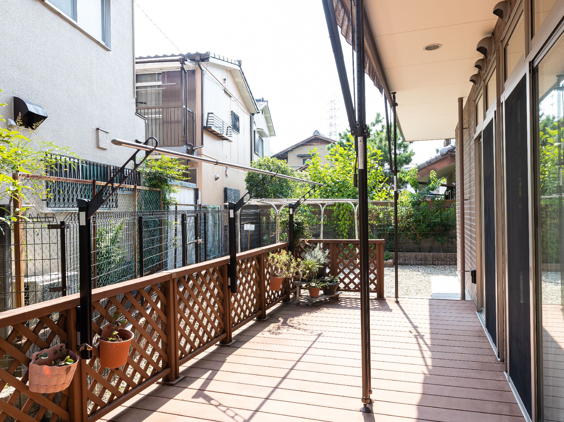 陽光が降り注ぎ、鉢植えの植物が置かれているウッドデッキ