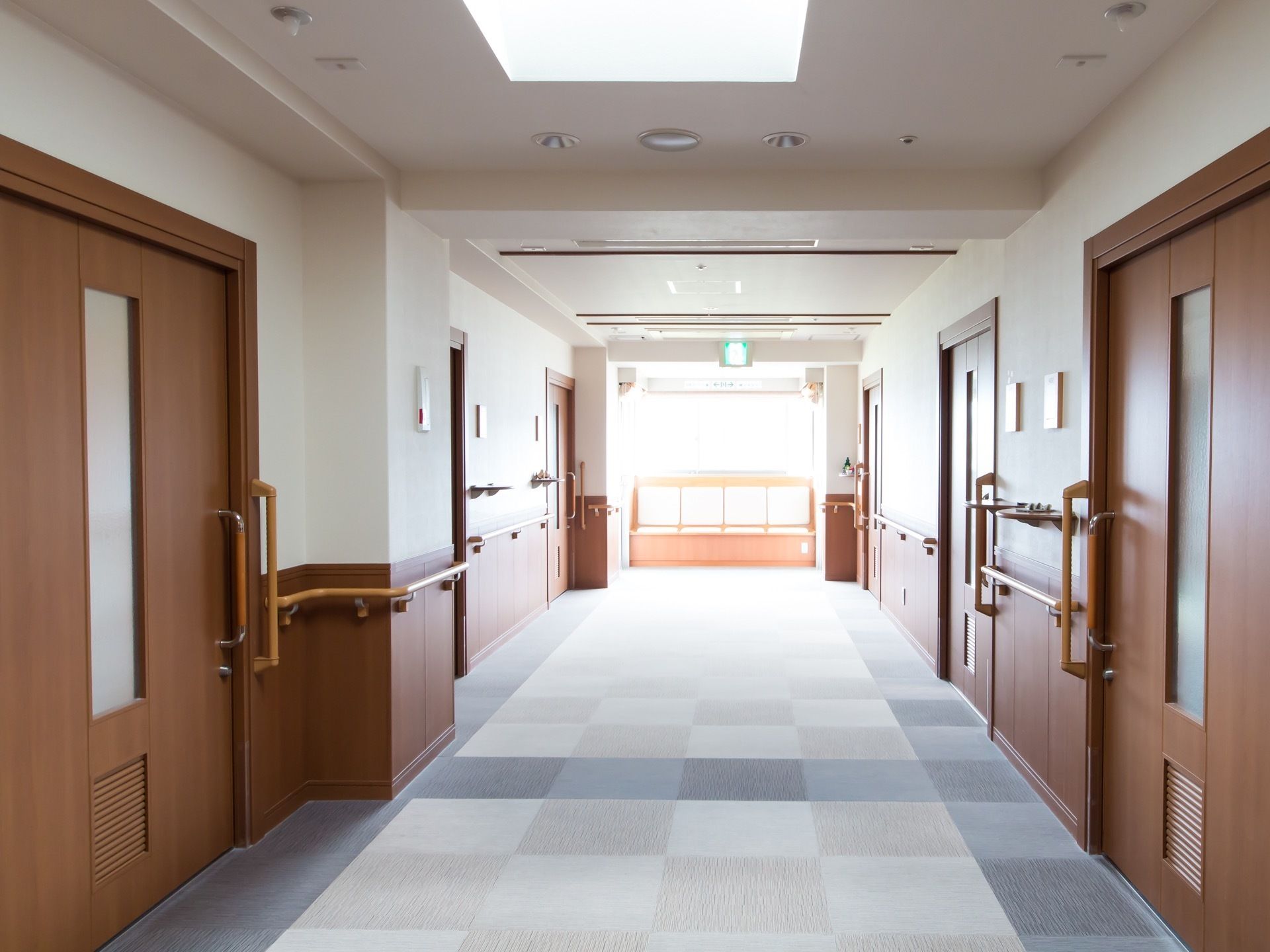 廊下はつきあたりの窓からの採光や照明で明るくなっている。床面にはマス目模様のカーペットが敷かれている。