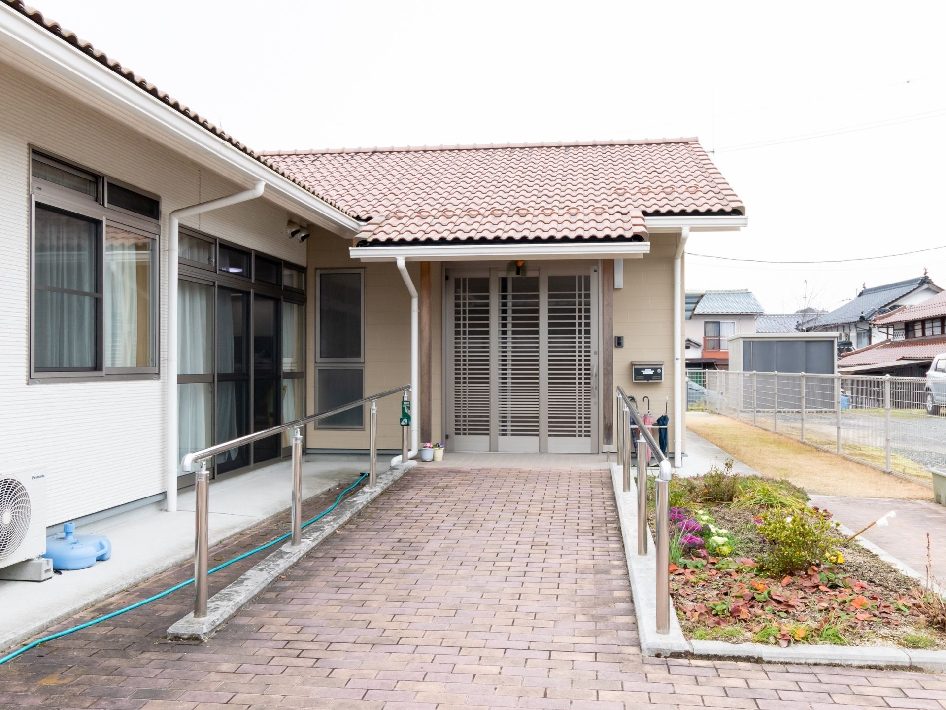ゆるやかなスロープの先に玄関がある。スロープの両側には手すりが設けられ、使いやすさ、安全性への配慮が行き届いている。