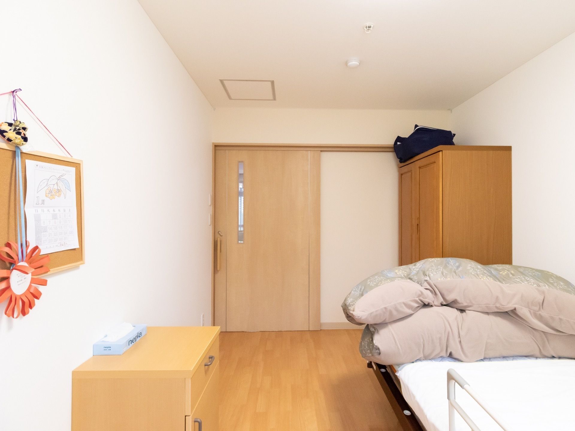 部屋への入り口は横幅の広いスライドドアになっている。室内にはベッドやタンス、棚などが設置されている。