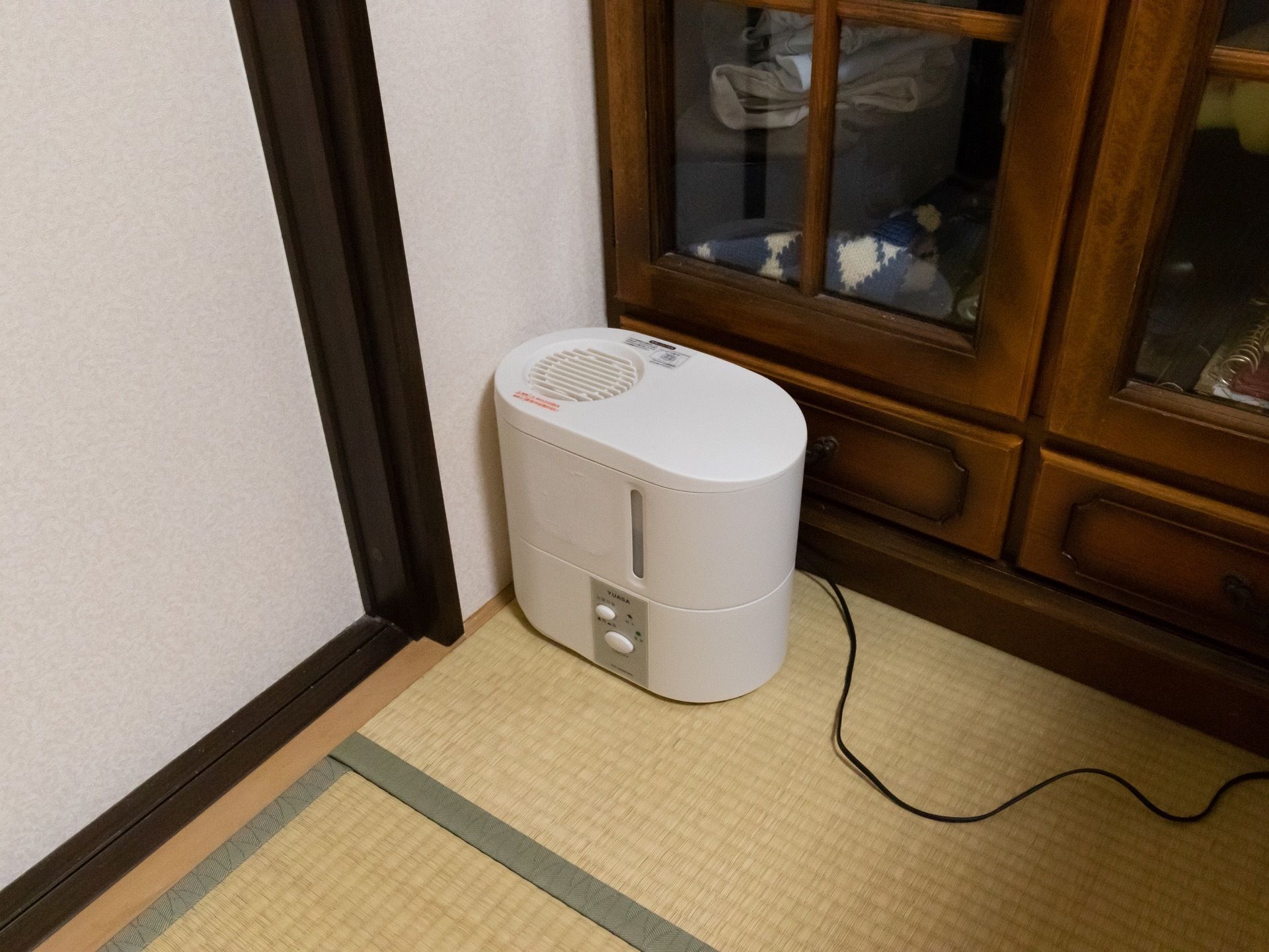 居室のタンスの前に加湿器が置かれている。シンプルな構造でボタンが２つしかなく操作しやすい。床は畳である。