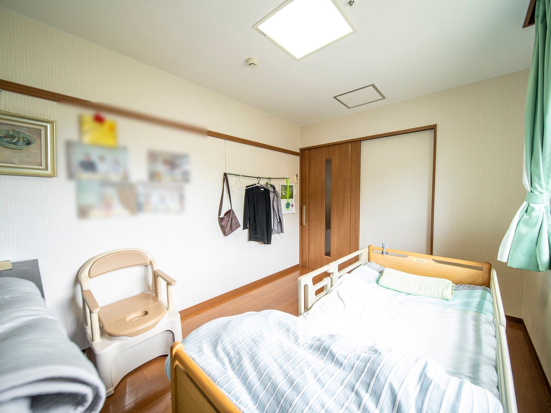 居室の壁には写真やカレンダーが飾られている。肘付きの椅子がベッドの近くに置かれており、くつろいだあとすぐに寝ることができる。