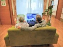 ソファに座ってテレビ鑑賞を楽しんでいる2名の入居者の後ろ姿。