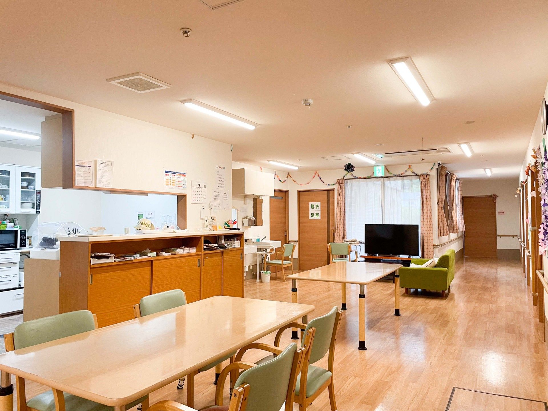 日当たりのいい共有スペースのダイニングテーブルに入居者が集まり、おやつを食べている。