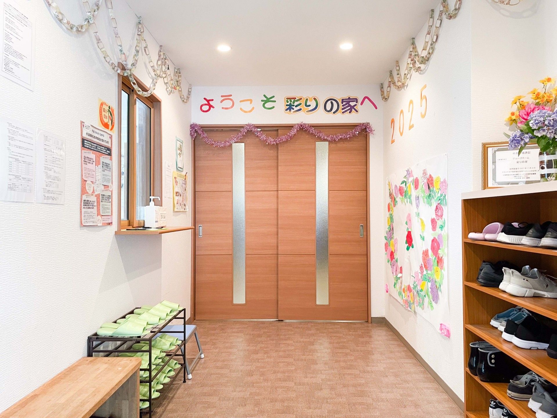 テレビの前のグリーンのソファに座った2名の入居者がテレビを見ている。