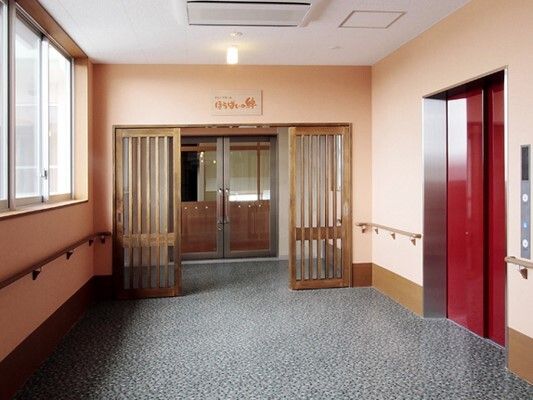 まっすぐな廊下の両サイドに手すりが付いている。エレベーターもあり、赤い扉が付いている。