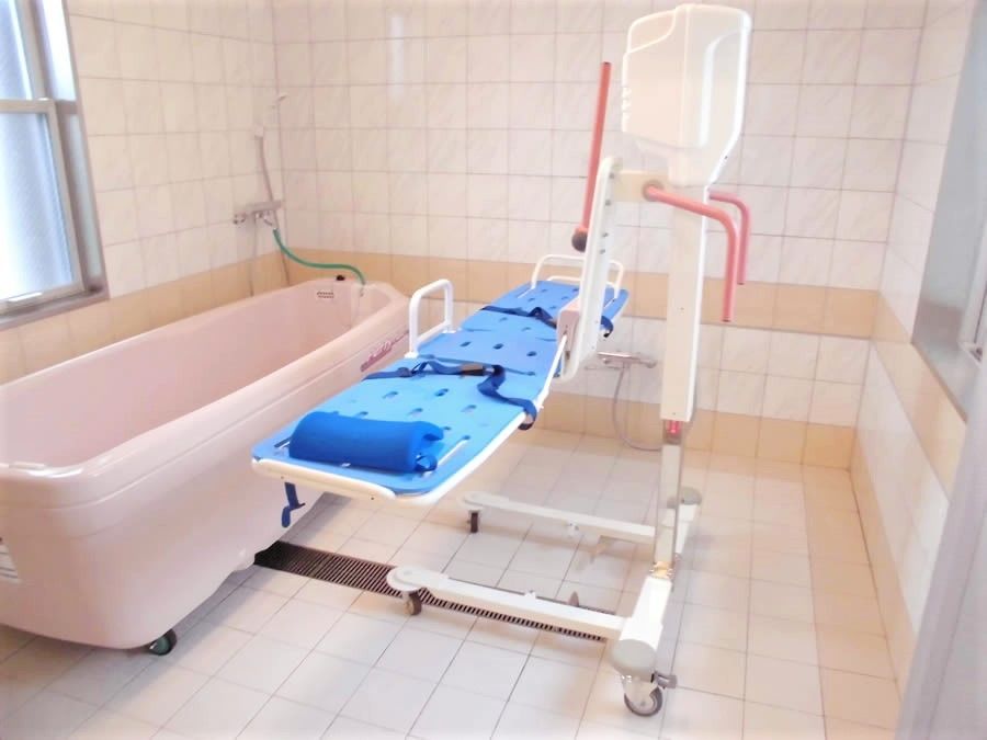 ピンクと白の寝台浴が完備され、介護度の高い人にも対応している浴室は明るい。