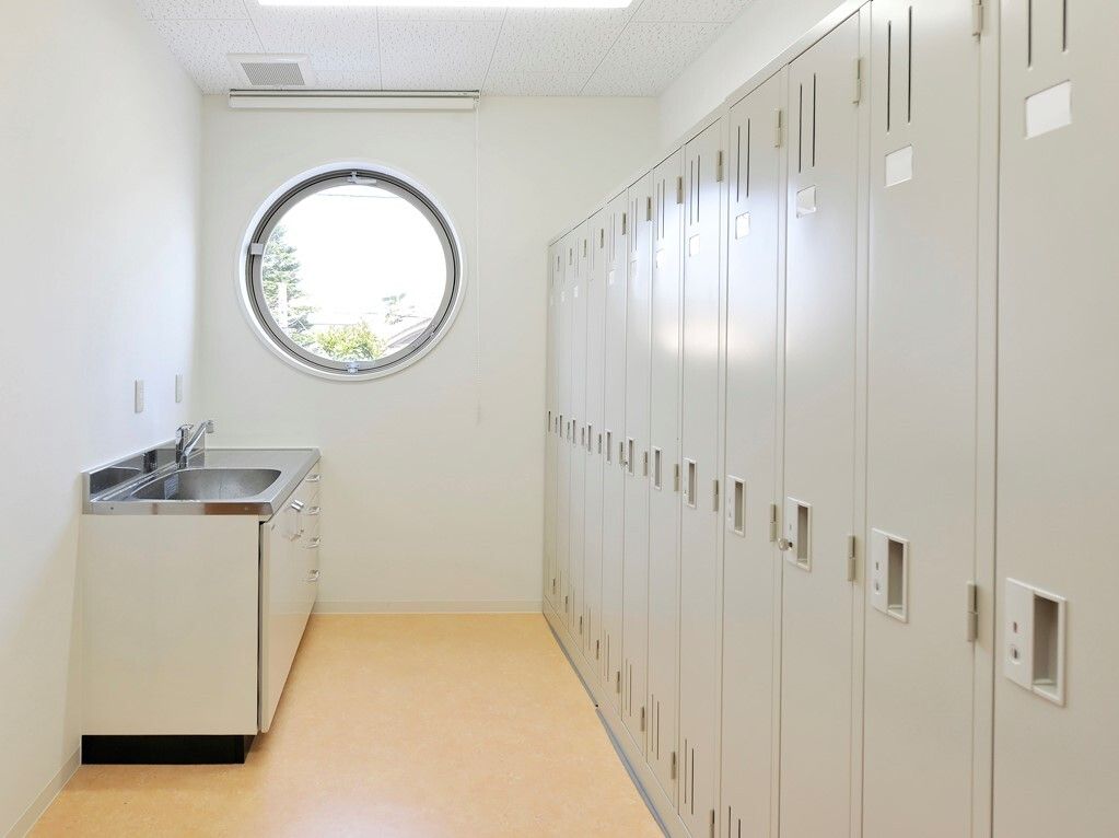 奥の方に丸い窓がついている更衣室の様子。ロッカーが並べられている更衣室