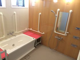 手すりが設置された家庭的な浴室には、手すりやベンチが設置されている。