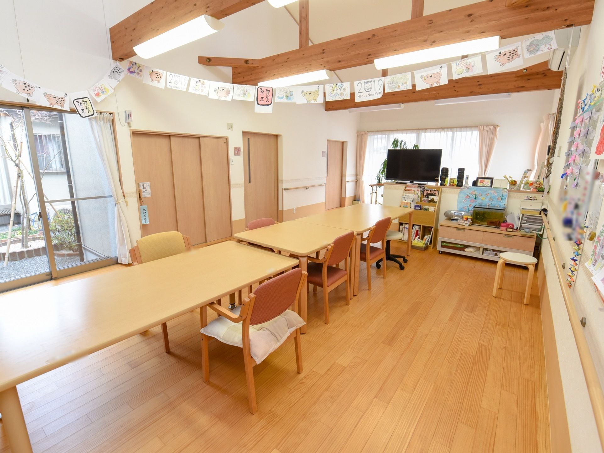 天井が吹き抜けになっている食堂がある。椅子とテーブルが並べられ、天井や壁には飾りつけがされている。大きな窓があり、日当たりが良い。