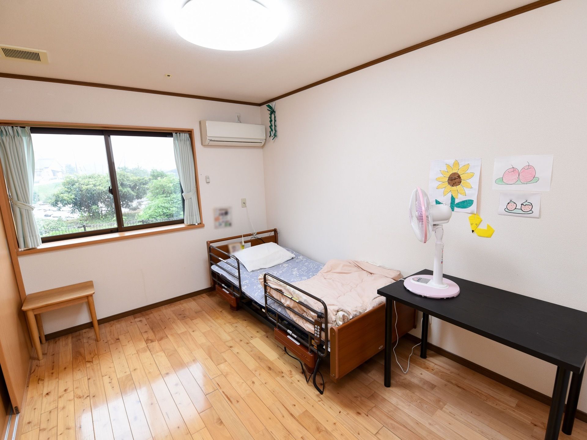 窓から陽射しが差し込む明るい居室では、外の景色を楽しむことができる。エアコンが設置されており、一年を通して快適に過ごせる。