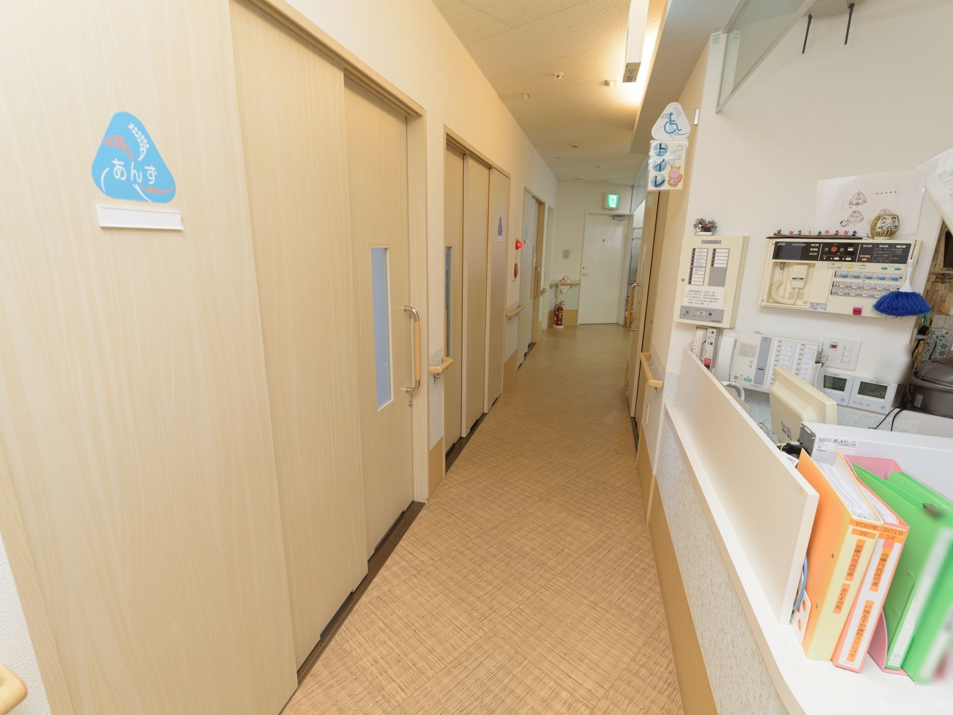 車椅子が通れる広さの廊下である。右にダイニングがあり、左に居室が設けられている。手すりが壁に備えつけられている。