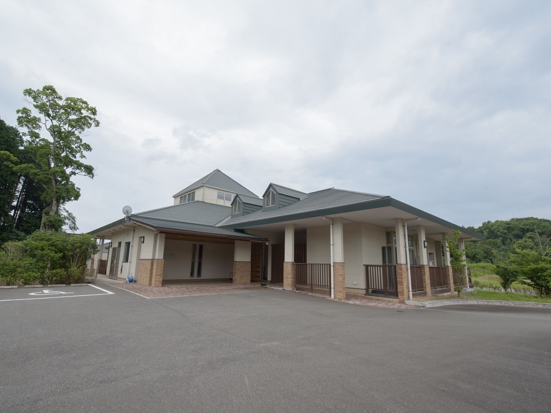施設はグリーンの三角屋根が特徴的な洋風の建物である。エントランス前に身障者用の駐車スペースが設けられている。