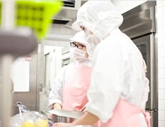 業務用のキッチンで調理している様子。白衣を着た専門スタッフが調理しているのが分かる