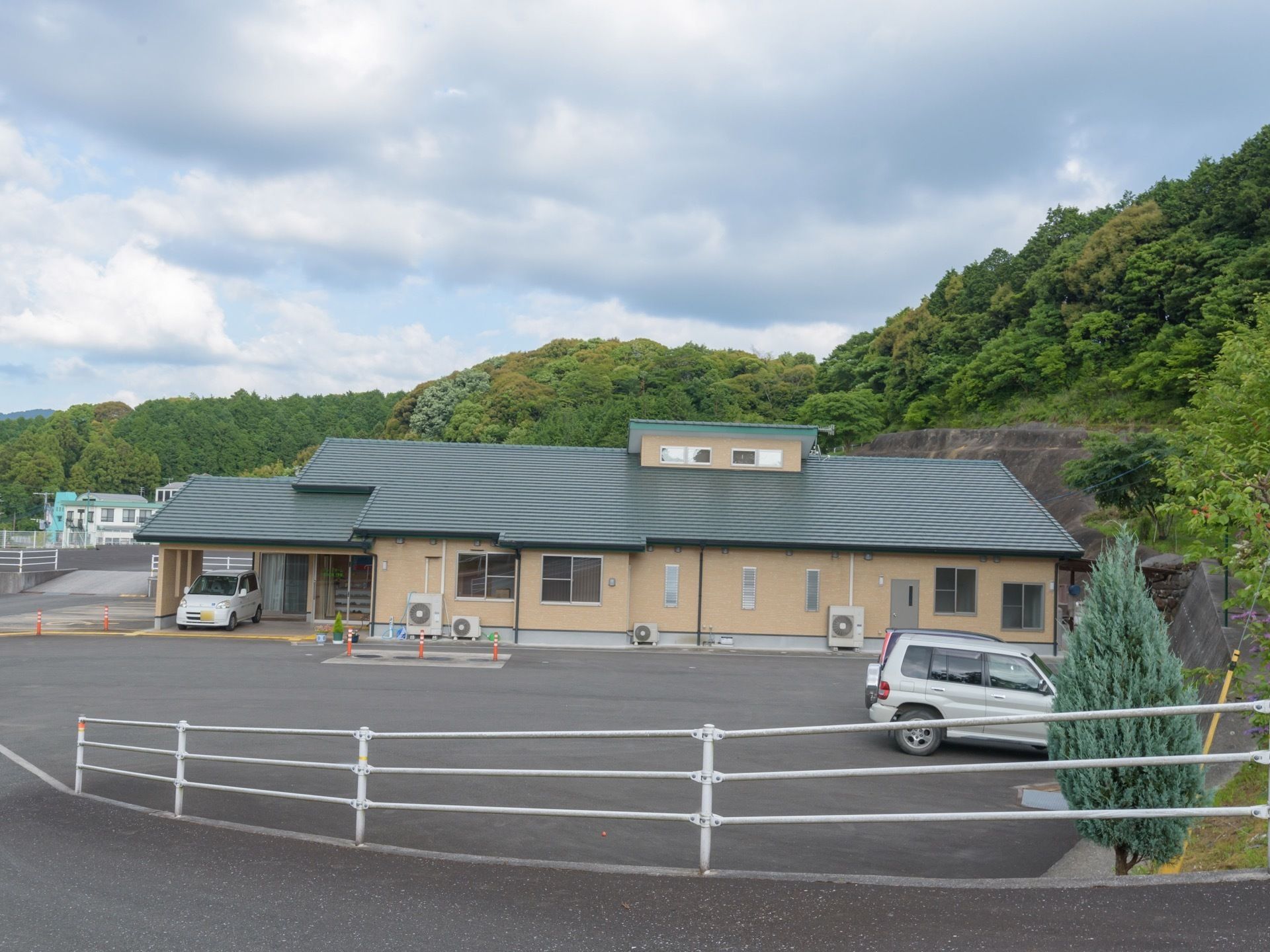自然に囲まれた環境の中に建っている施設。建物前に駐車スペースが用意されている。車寄せが玄関ポーチに設けられている。