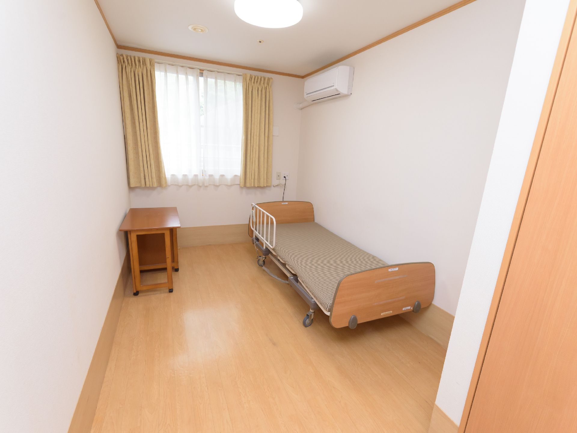 未使用の介護用ベッドが置かれた窓が設置されているご入居前の居室