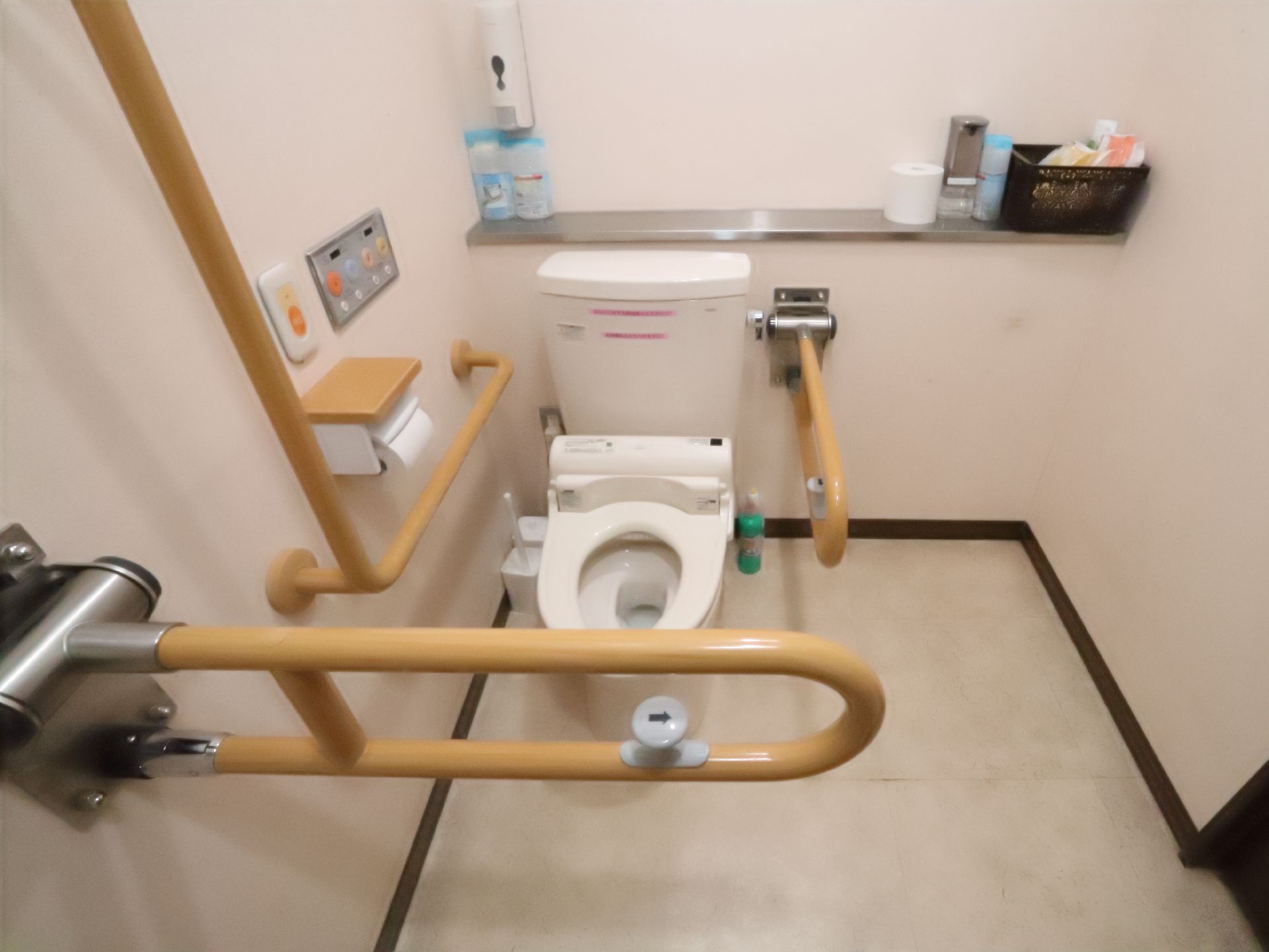 木製の手すりに囲まれた洋式便器が置いてある白い壁の部屋