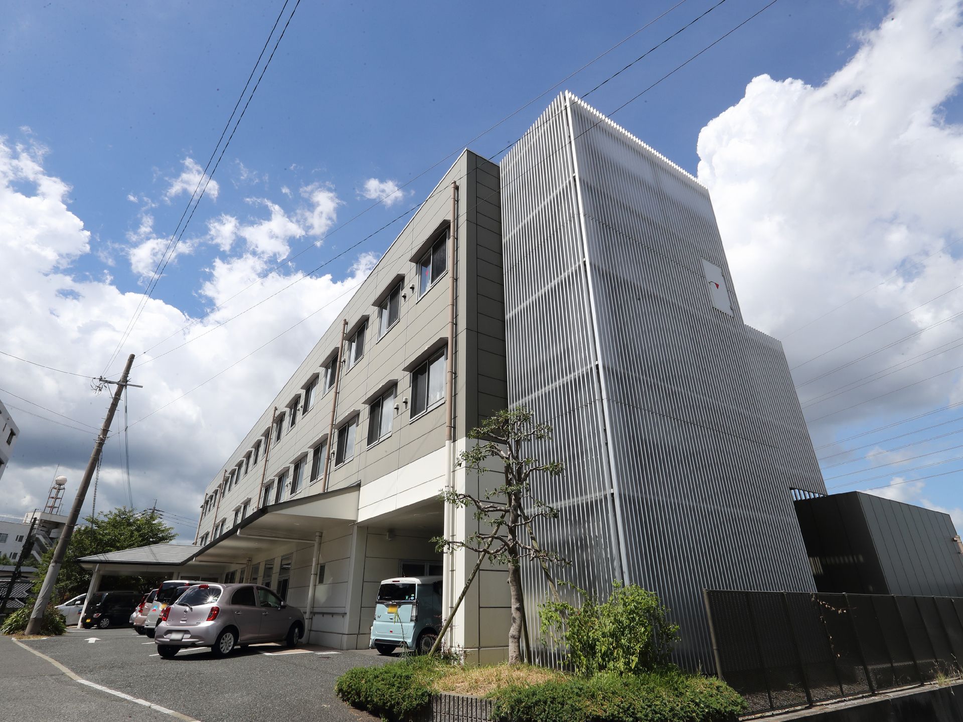 アスファルト沿いに立地しているグレーの外観で３階建ての建物