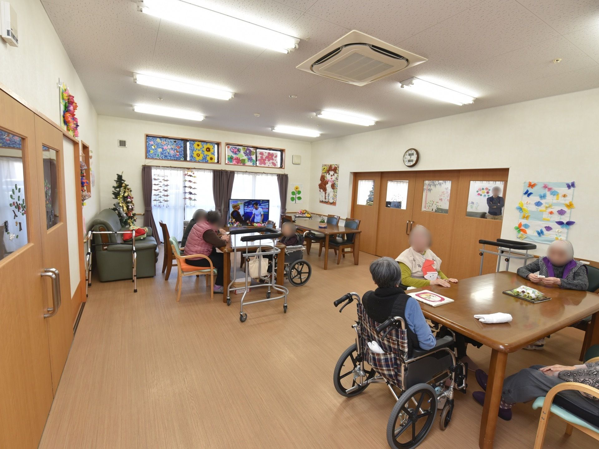 両側に茶色いドアのある広い談話室。テーブルと椅子、大きなソファが置かれている。窓際にはテレビがあり、壁には飾りつけがされている。