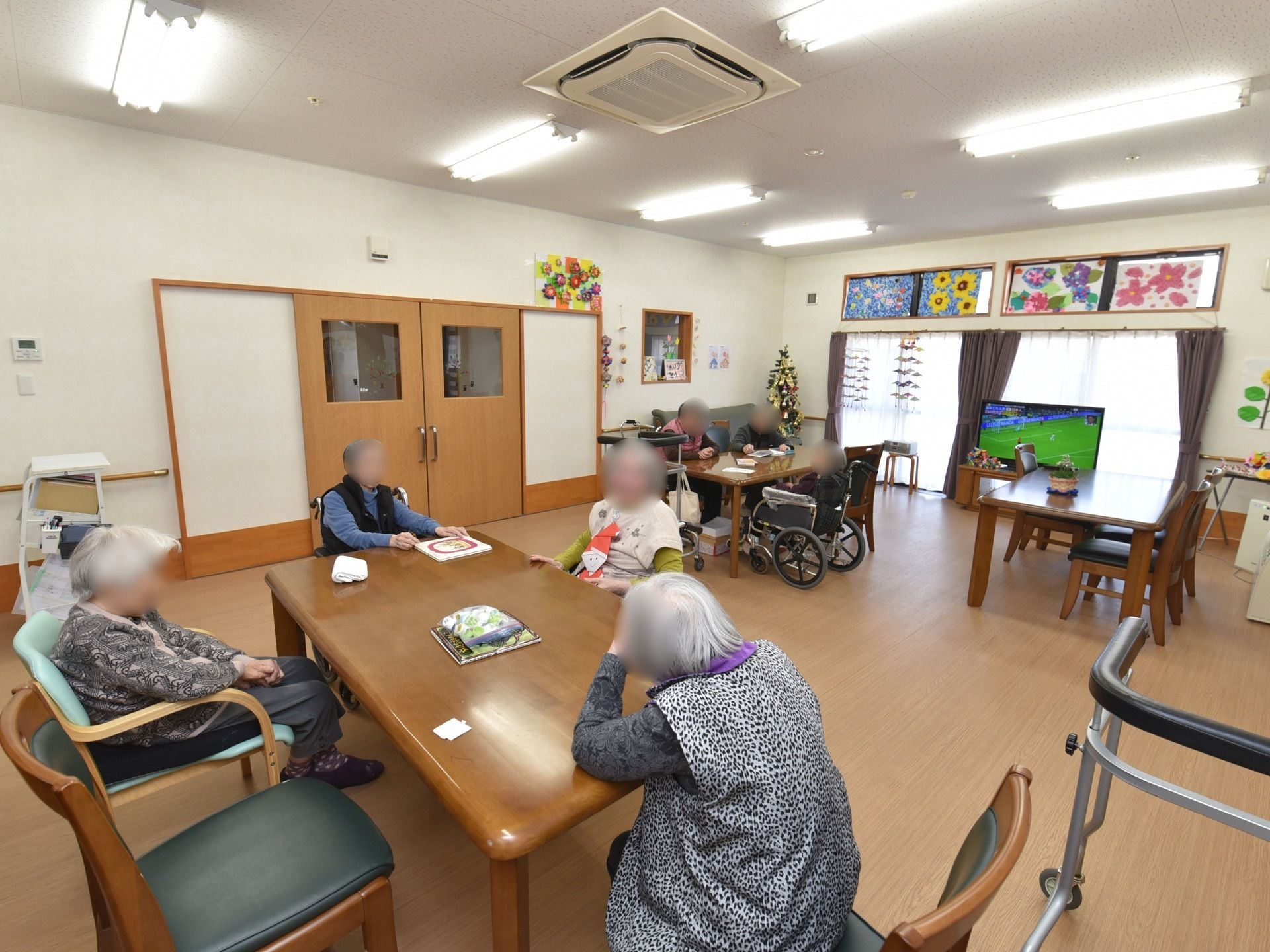 テーブルと椅子、ソファが置かれている談話室。大きなテレビが置かれている。テーブルの間のスペースが広くとられている。