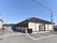 日本家屋風の平屋建ての大きな建物がある。敷地内には駐車場があり、地面には駐車スペースを示した白線が描かれている。