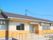 グレーの屋根が付いた平屋建ての建物は日当たりのいい場所に建っている。玄関先には屋根と手すり付きのスロープがある。