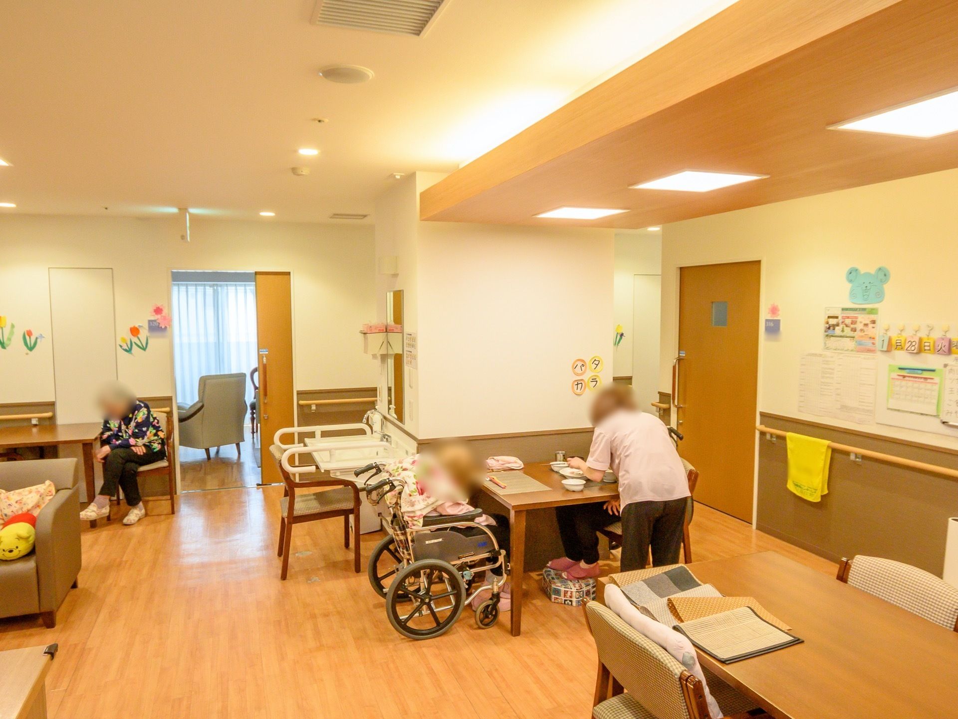 木製のテーブルに肘掛付きの椅子が設置されている。奥に手洗い場、その奥には居室がありスライド式のドアが開いている。