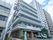 ６階建ての建物。壁は薄い緑と白で１階部分だけベージュ。手前にトラックが停まっている。入居者募集の看板が掛けられている。