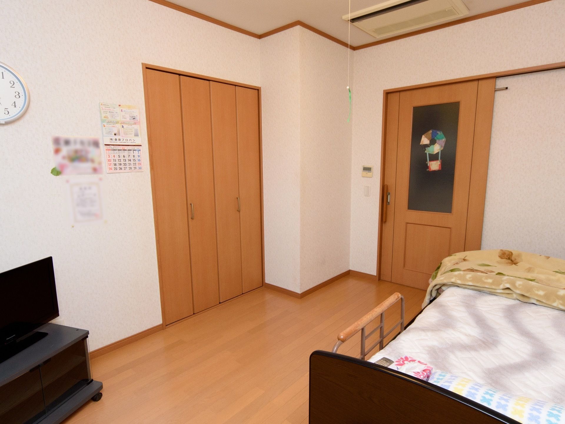 居室はワンルームタイプで、明るく広々としている。家具を壁に寄せて配置し、真ん中は広く通路として空けられている。