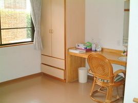 収納家具や鏡台のようなテーブルセットが設置された居室。テーブルの上には小物が置かれている。