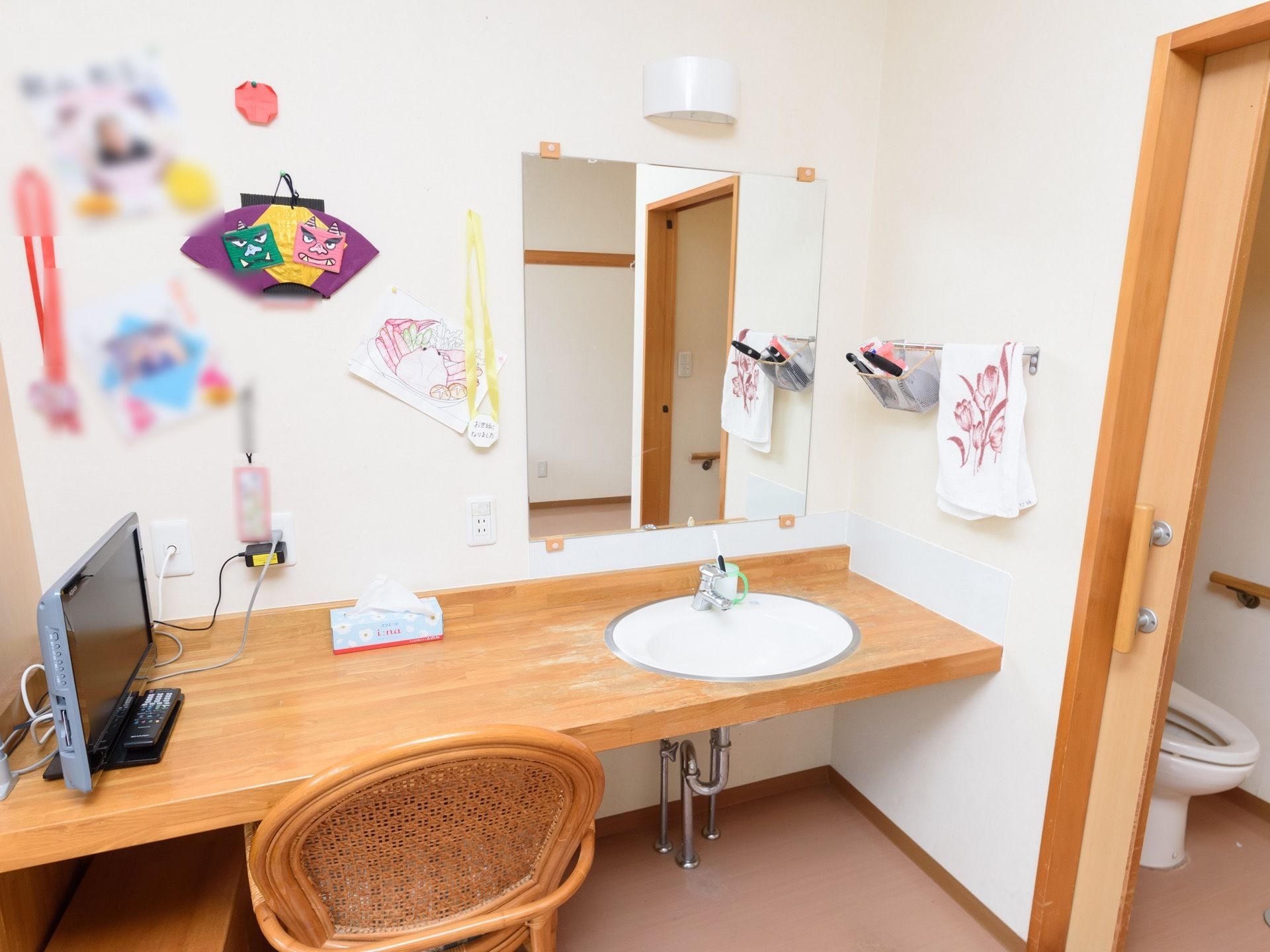 居室の壁際には、机も兼ねた広い洗面台が設置されている。照明や鏡、タオルハンガーが壁に取りつけられている。