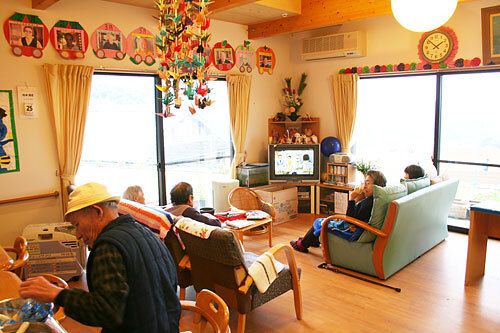 日当たりのいいリビングダイニングでくつろぐ入居者たち。テレビを見たり工作をしたりと思い思いに過ごしている。