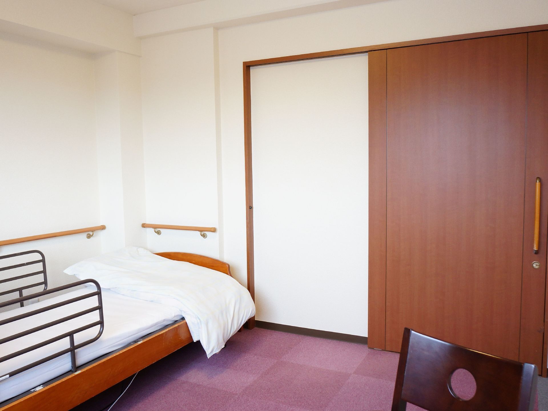 居室の床にはローズ系のカーペットを敷き詰めている。入り口の扉は木製で、大型のハンドルを取り付けている。