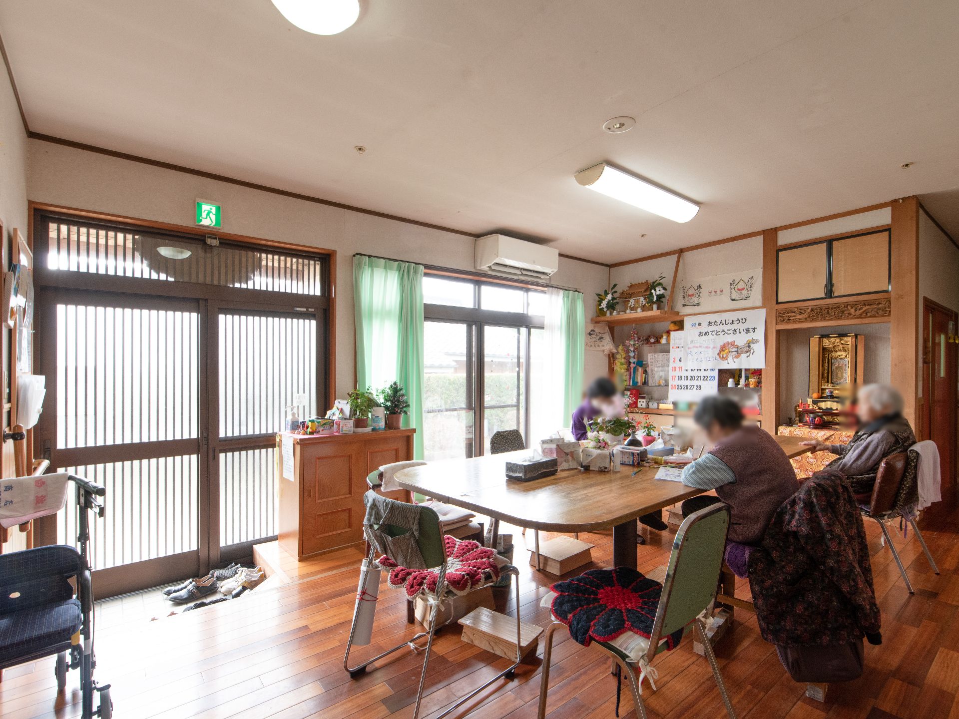 左奥に引き戸の玄関扉があり、その前にサンダルなどが並んでいる。ドアの前にチェストが置かれ、植木鉢などが飾られている。