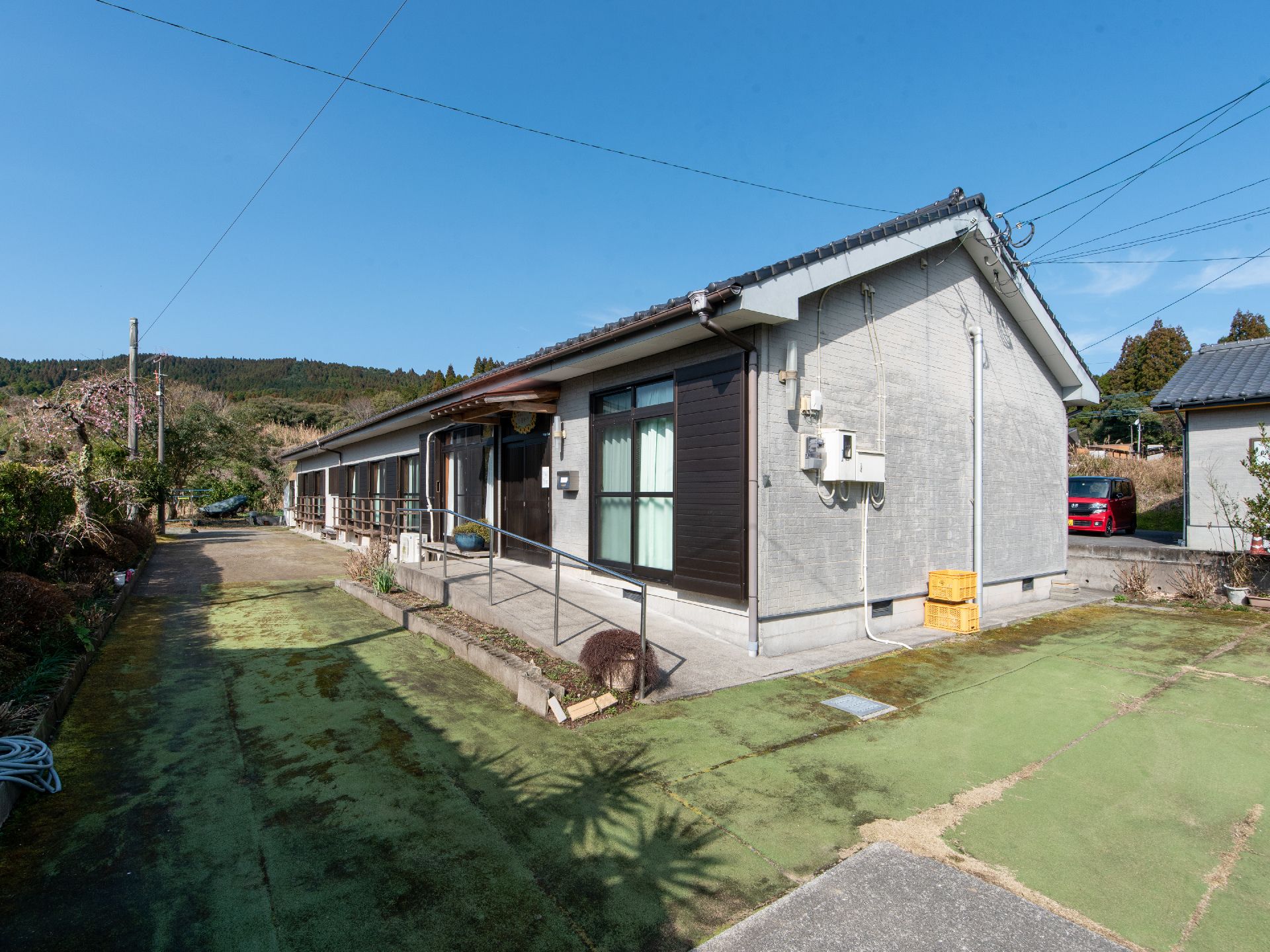 瓦屋根で横に長い平屋建ての建物である。建物の周囲は段差のないコンクリートで舗装されており、木々が植えられている。