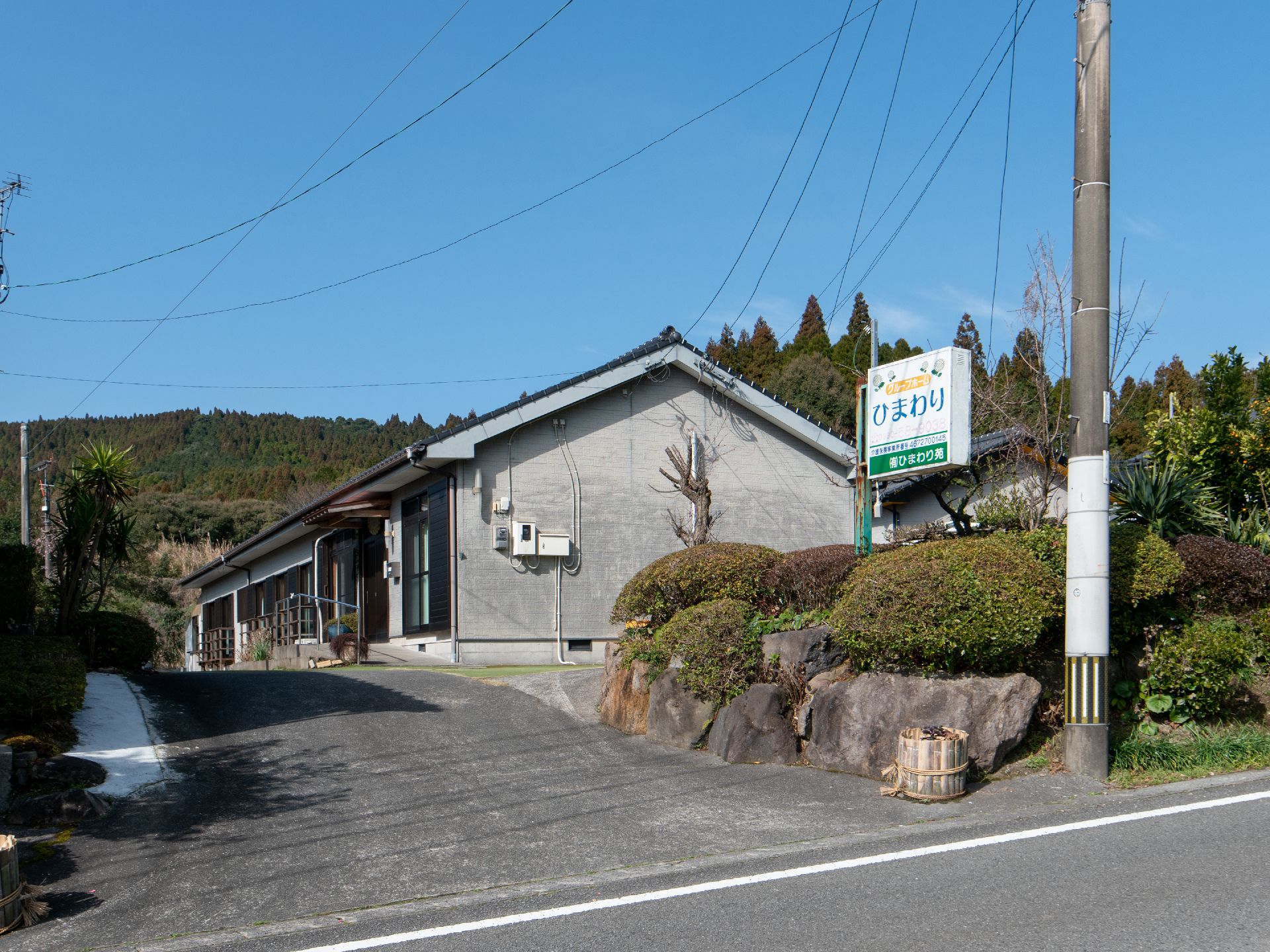 道路に面した施設で、敷地内入口に看板が掲げられている。敷地内には多くの木が植えられており、自然が多く見られる。