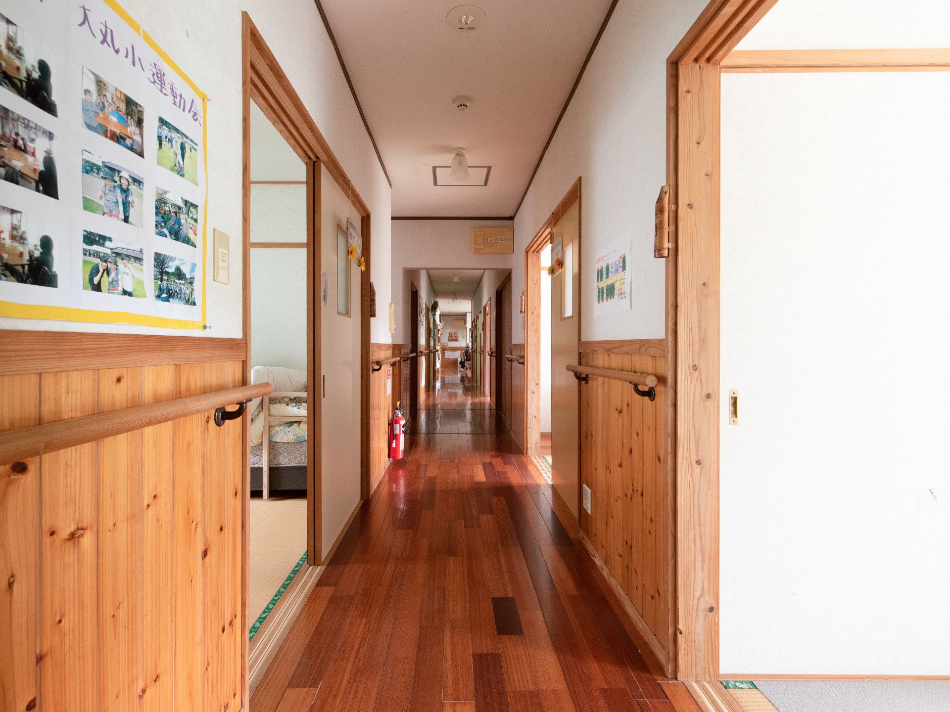真っ直ぐに伸びた廊下になっており、廊下の両側に居室の入口が並んでいる。壁には行事の写真が飾られている。