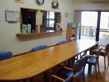 木製のテーブルと椅子が置いてあるリビングスペース。奥のほうにカウンター式のキッチン