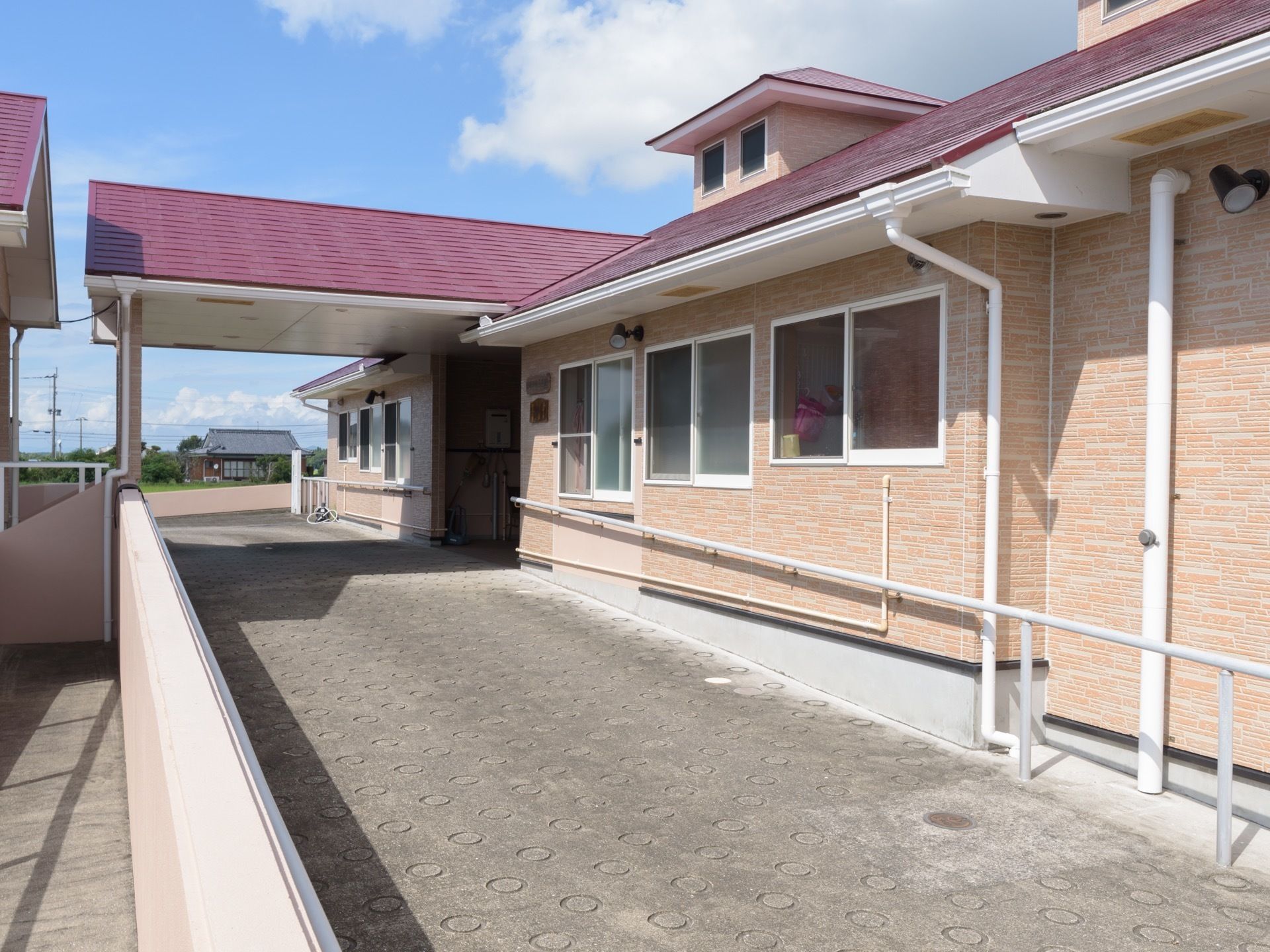 オレンジ系の細いタイルが貼られた外壁に、紫色の屋根が乗った建物である。玄関までは緩やかなスロープになっている。
