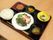 黒いトレーに、ご飯、スープ、魚料理、煮物、ブロッコリーのサラダが並べられている。食後のデザートとして、どら焼きも添えてある。