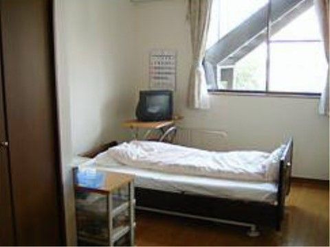 介護用ベッドの側の壁際にテレビが椅子の上に置かれて設置されている居室