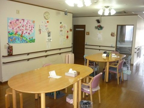 リビングルームにはテーブルと椅子が置かれ、それぞれに寛ぐことができる。壁には入居者様が作った壁画があり、アットホームな雰囲気である。