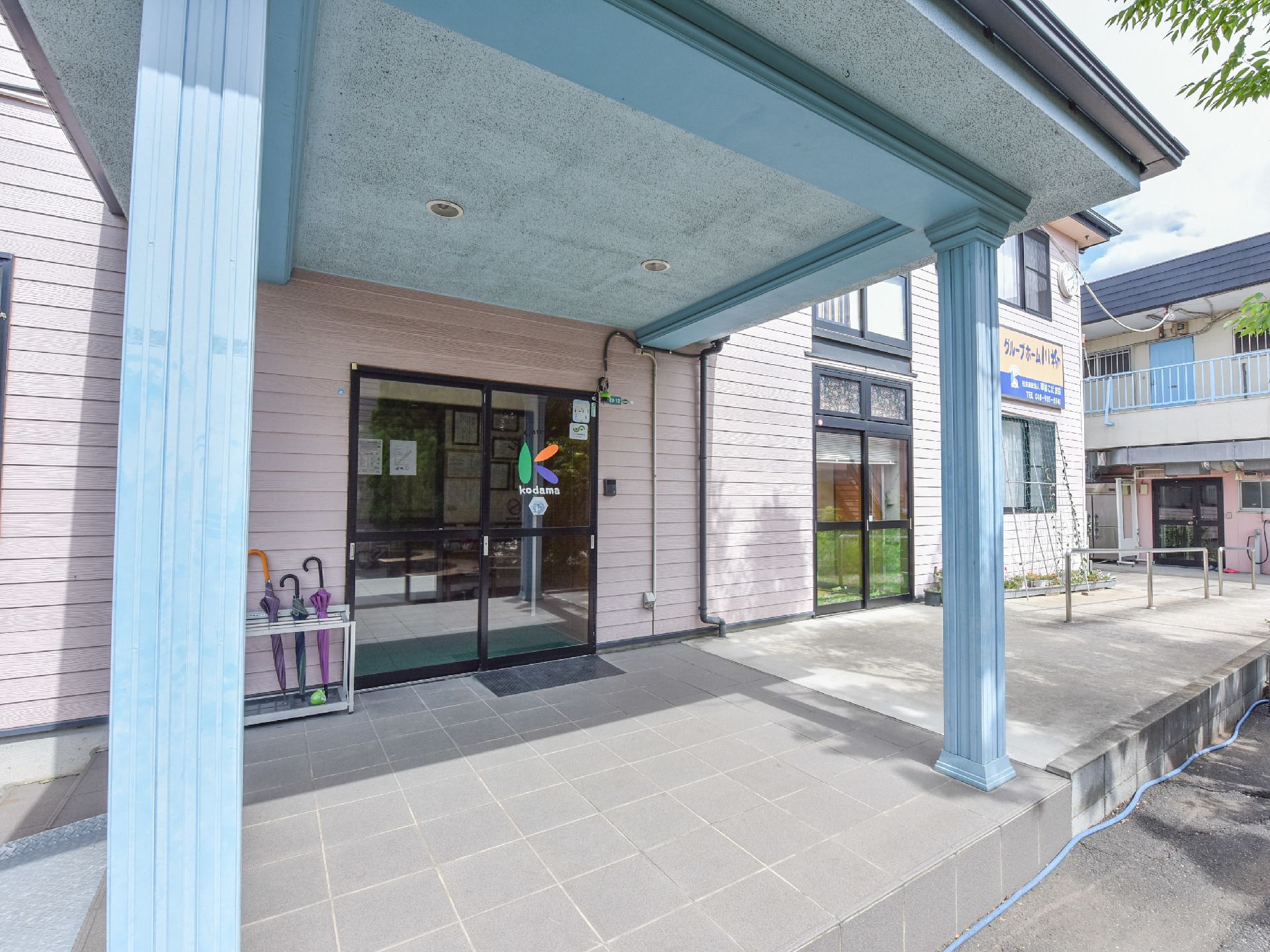 日当たりが良い。建物に施設名のついた看板が掛けられている。玄関前に呼び出しボタンがある。部屋の前に花壇がある。