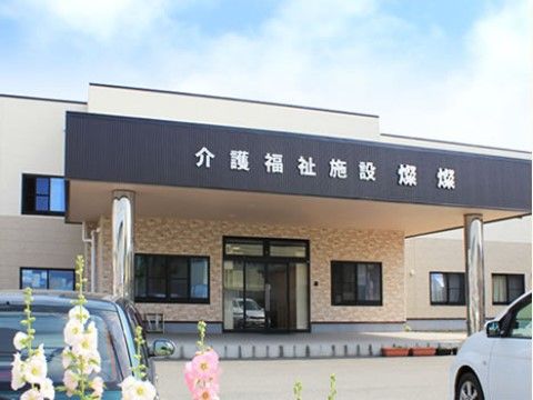 施設の建物の玄関には屋根が設置され、施設名が表示されている。入り口の前のスペースは広く、バリアフリーの設計になっている。