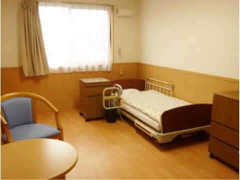 介護用ベッドに補助ホルダーが設置され窓際に置かれている居室