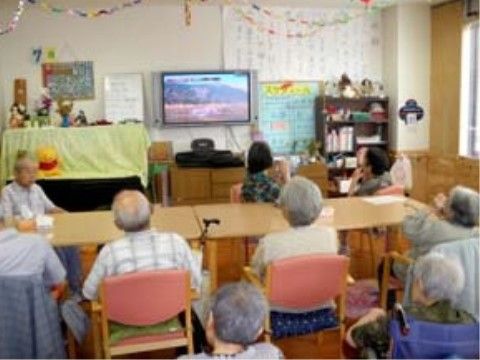 入居者様皆さまが集いテーブルの席に着きテレビ鑑賞をされている共有スペース